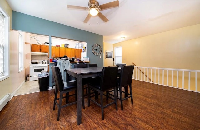 dining room featuring a baseboard radiator, plenty of natural light, ceiling fan, and light wood-type flooring