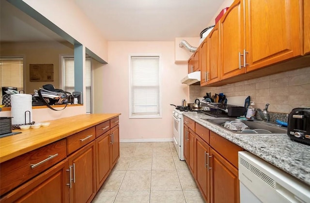 kitchen with light tile patterned flooring, tasteful backsplash, dishwashing machine, white range with gas stovetop, and light stone counters