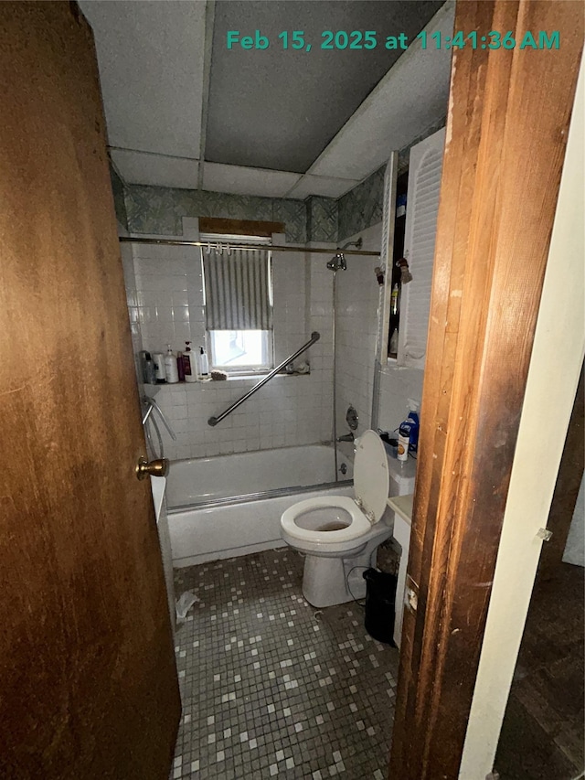 bathroom with tiled shower / bath combo, tile patterned floors, and toilet