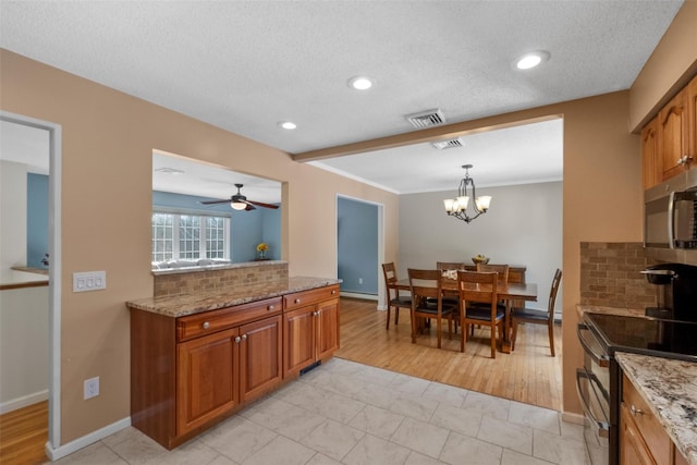 kitchen with decorative light fixtures, light stone counters, range with two ovens, and decorative backsplash