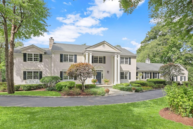 greek revival house with a front yard and a chimney