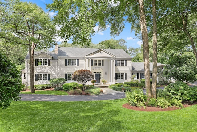 greek revival inspired property featuring a chimney and a front yard