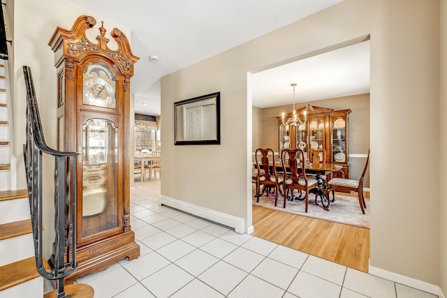 tiled entryway featuring a baseboard heating unit and an inviting chandelier