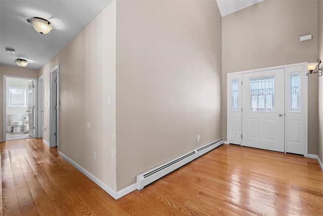 entryway with a baseboard heating unit, light wood-style floors, and baseboards