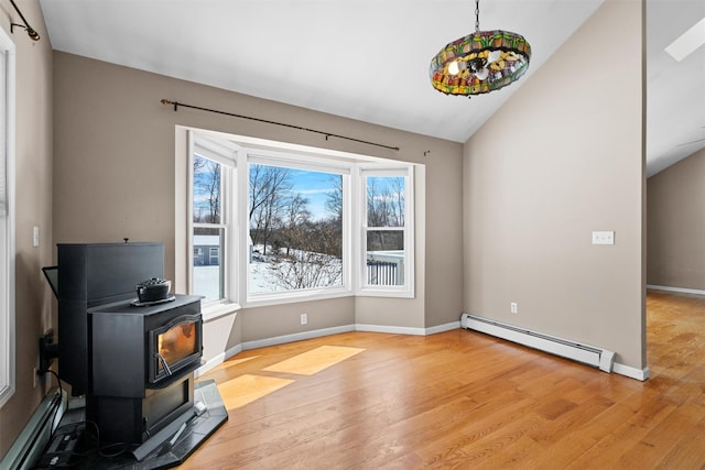 interior space featuring a baseboard heating unit, a wood stove, a healthy amount of sunlight, and light wood finished floors