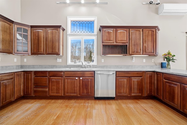 kitchen with light wood finished floors, light countertops, stainless steel dishwasher, a wall mounted AC, and a sink