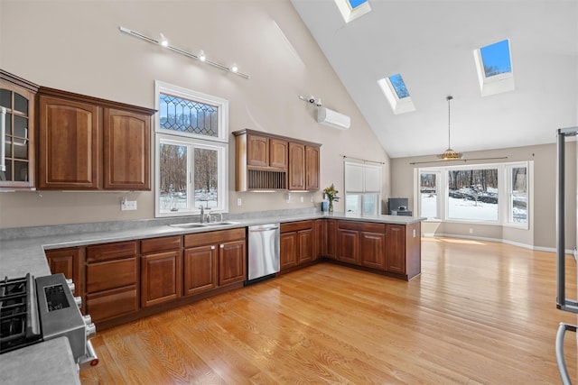 kitchen with a skylight, stainless steel appliances, light countertops, glass insert cabinets, and a sink