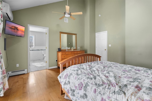 bedroom with light wood finished floors, visible vents, baseboard heating, a wall mounted AC, and high vaulted ceiling