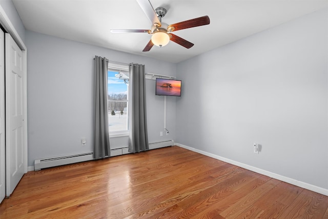 unfurnished room featuring a baseboard radiator, light wood-style flooring, and baseboards