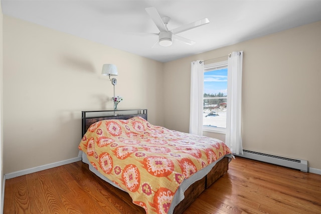 bedroom with a baseboard radiator, baseboards, and wood finished floors