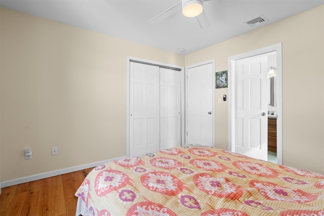 bedroom with baseboards, visible vents, ceiling fan, wood finished floors, and a closet