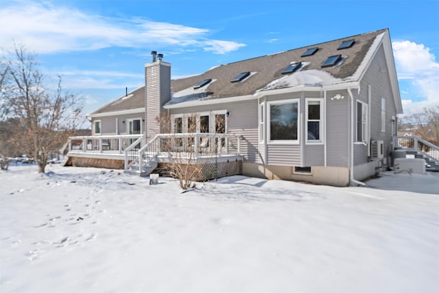 snow covered house with a chimney and a deck