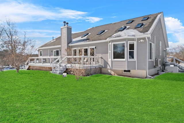 rear view of property with a deck, a yard, and a chimney