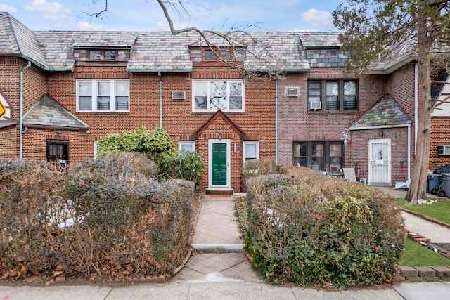 townhome / multi-family property featuring a high end roof, brick siding, and mansard roof