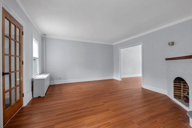 unfurnished living room featuring ornamental molding, a brick fireplace, wood finished floors, and baseboards