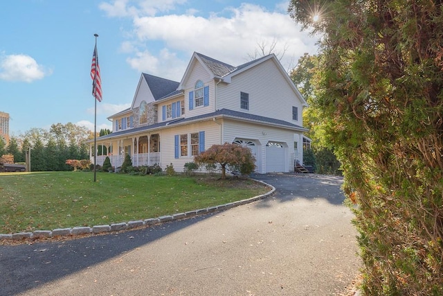 view of front of house with covered porch, a front lawn, a garage, and aphalt driveway