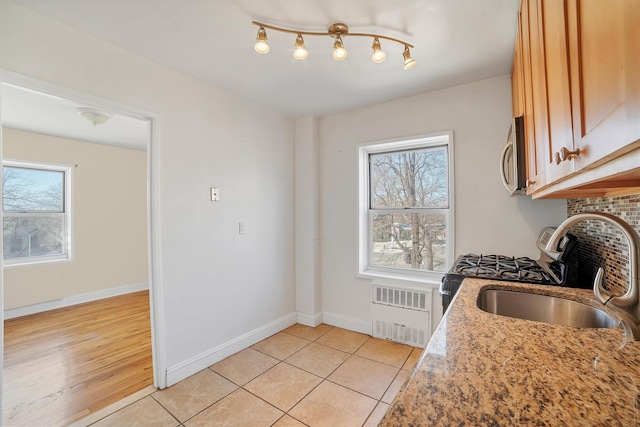 kitchen with backsplash, baseboards, light tile patterned floors, appliances with stainless steel finishes, and a sink