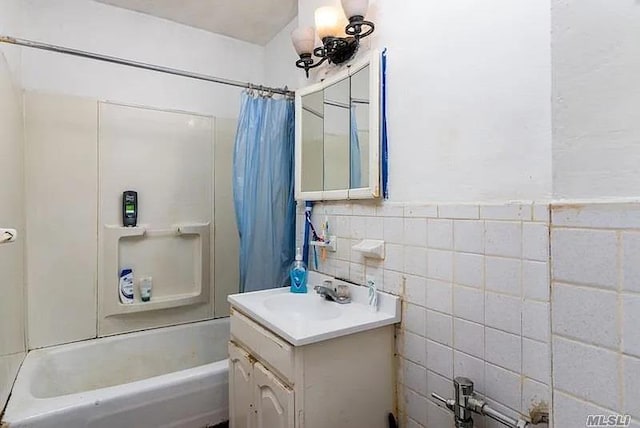 bathroom featuring tile walls, vanity, and shower / bath combo