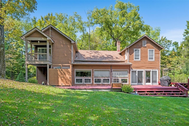 back of house with a deck, roof with shingles, a yard, and a chimney