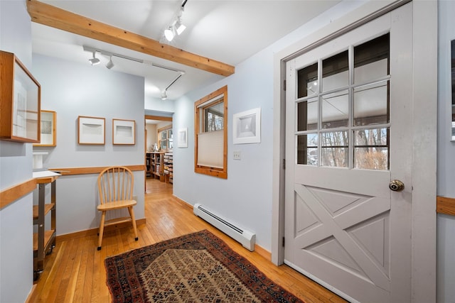 doorway to outside featuring a baseboard heating unit, beam ceiling, rail lighting, and light wood finished floors