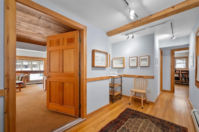 hall with a healthy amount of sunlight, light wood-style flooring, and a baseboard heating unit