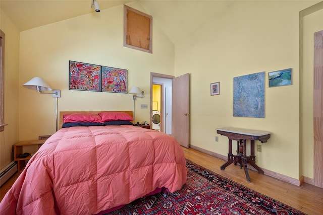 bedroom with washer / dryer, light wood-type flooring, high vaulted ceiling, and baseboards