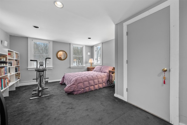 bedroom with multiple windows, dark carpet, and baseboard heating