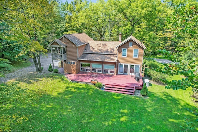 back of house with a balcony, a yard, roof with shingles, a wooden deck, and a chimney