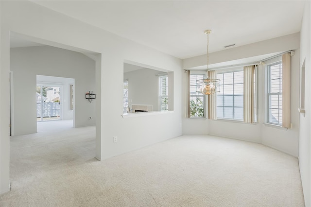 spare room with a chandelier, carpet flooring, and visible vents