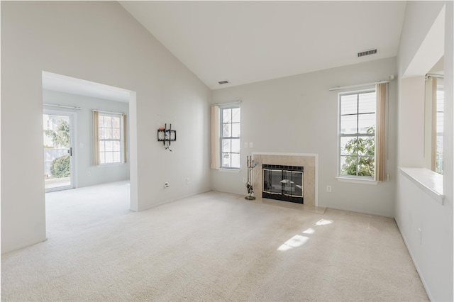 unfurnished living room with a fireplace, carpet flooring, visible vents, and a healthy amount of sunlight