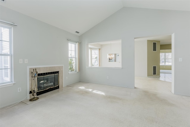 unfurnished living room with a high end fireplace, carpet flooring, vaulted ceiling, and visible vents