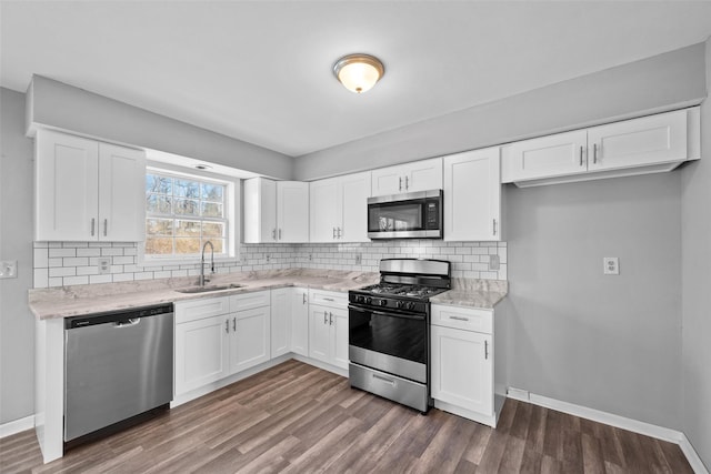 kitchen with sink, dark wood-type flooring, white cabinetry, stainless steel appliances, and tasteful backsplash