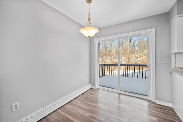 unfurnished dining area featuring baseboard heating and light wood-type flooring