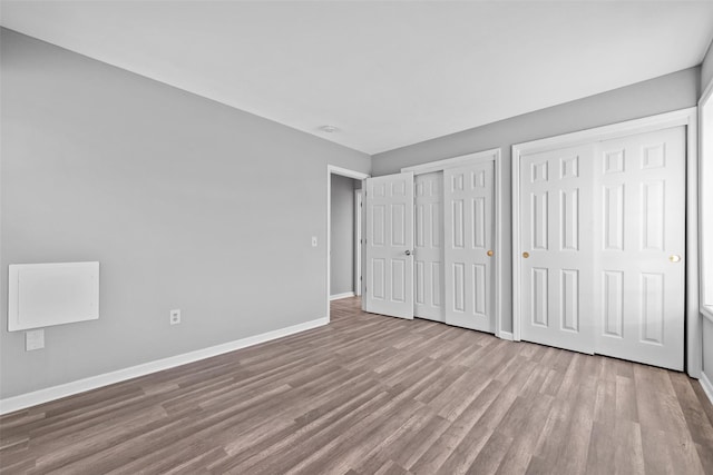 unfurnished bedroom with two closets and light wood-type flooring