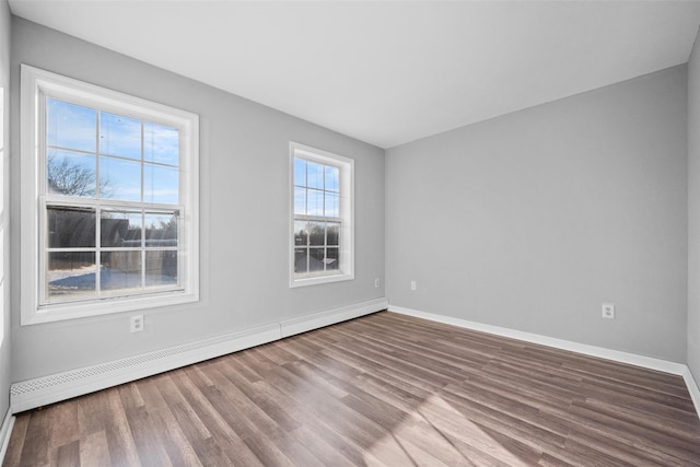 spare room featuring baseboard heating and hardwood / wood-style floors