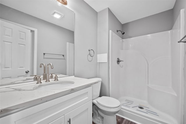 bathroom with walk in shower, vanity, toilet, and wood-type flooring