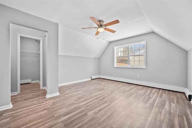 additional living space with ceiling fan, a baseboard radiator, vaulted ceiling, and light wood-type flooring