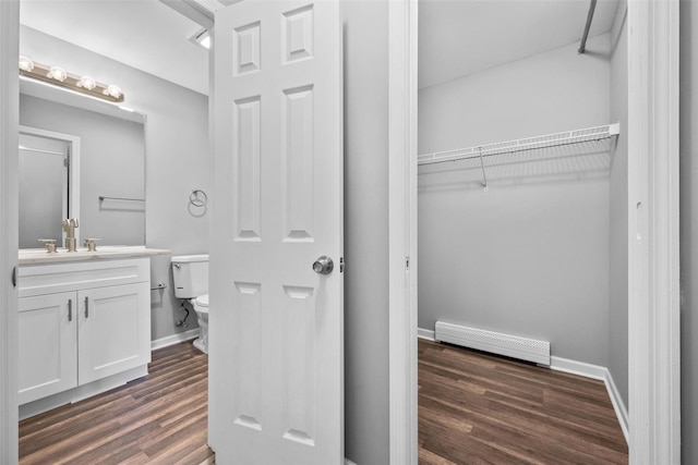 bathroom featuring a baseboard radiator, hardwood / wood-style floors, vanity, and toilet