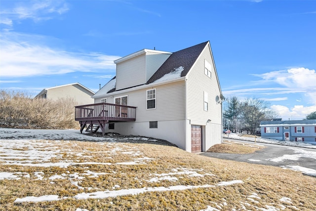 snow covered house with a wooden deck and a garage