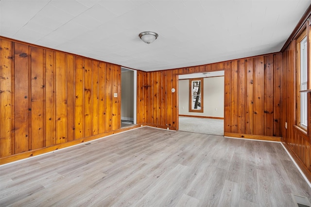 empty room featuring wood walls and light wood-type flooring