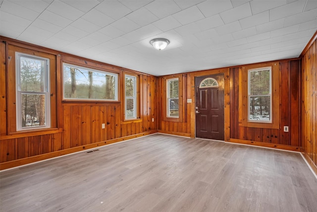 foyer with wooden walls and light hardwood / wood-style floors