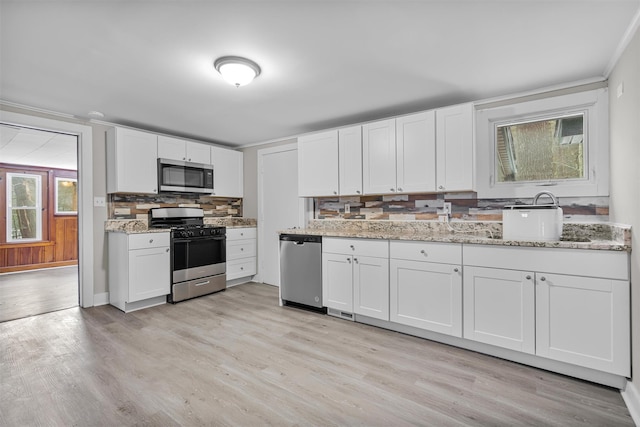 kitchen with stainless steel appliances, white cabinetry, and light stone countertops