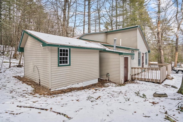 snow covered back of property featuring a deck