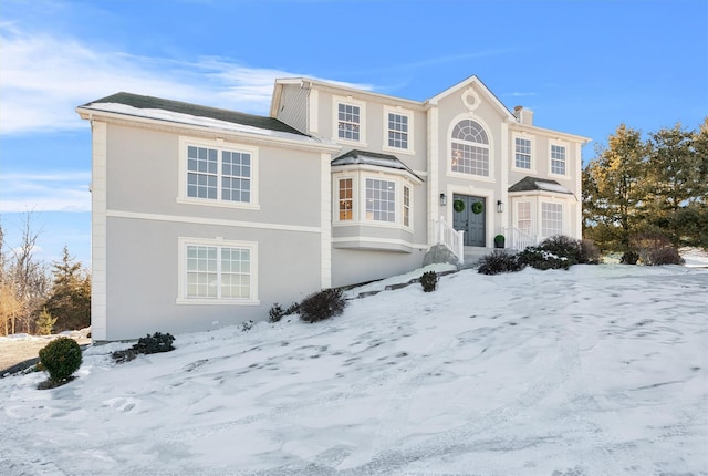 view of front of house with a chimney and stucco siding