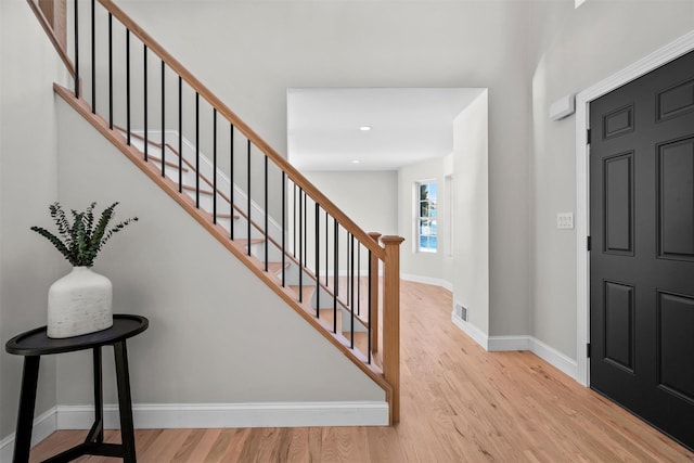 foyer featuring light wood-style floors, visible vents, stairway, and baseboards