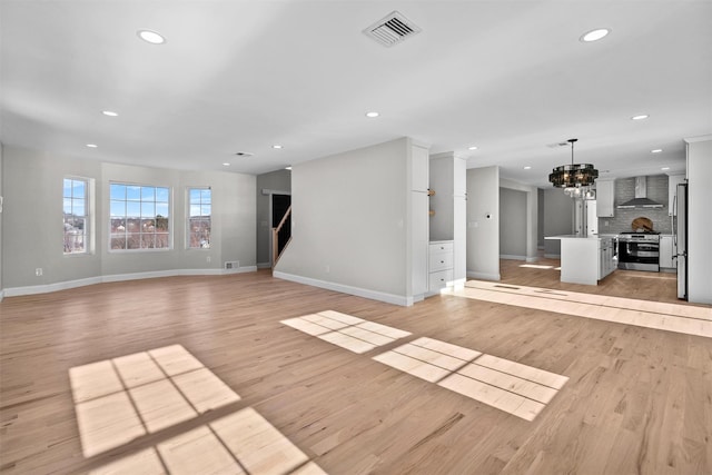 unfurnished living room with baseboards, light wood finished floors, visible vents, and recessed lighting