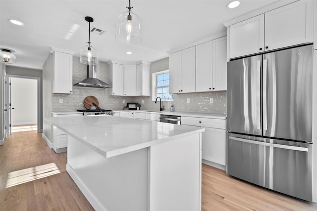 kitchen with a center island, stainless steel appliances, visible vents, white cabinets, and wall chimney exhaust hood