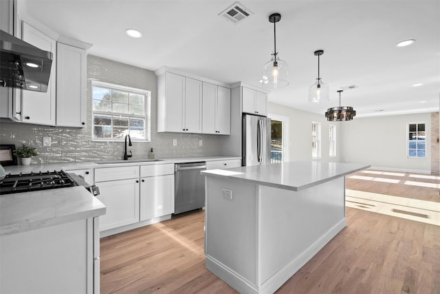 kitchen featuring a center island, visible vents, appliances with stainless steel finishes, white cabinets, and a sink