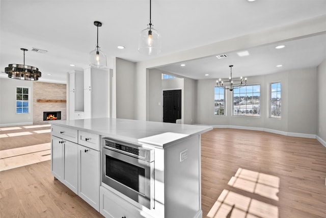 kitchen with open floor plan, decorative light fixtures, visible vents, and white cabinets