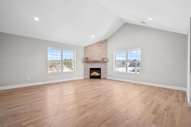 unfurnished living room featuring high vaulted ceiling, a stone fireplace, light wood-style flooring, recessed lighting, and baseboards